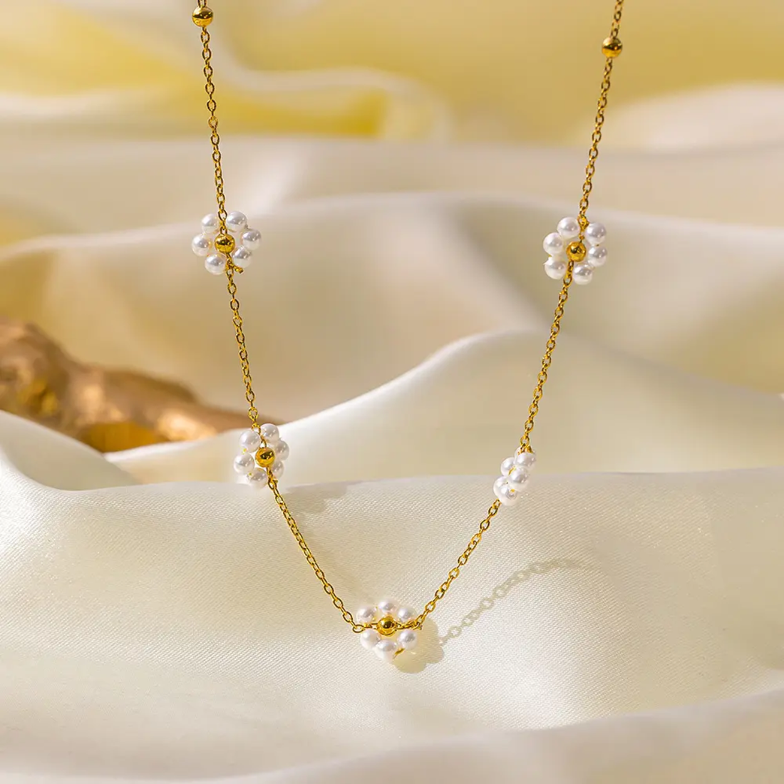 Gold necklace with floral beads on a soft white fabric background