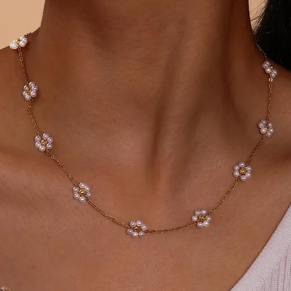 Necklace with floral pendants on a person wearing a light-colored top against a neutral background