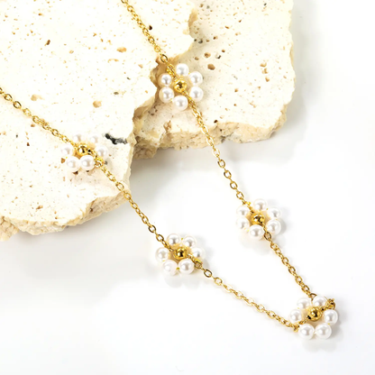 Gold necklace with pearl flowers on a white background